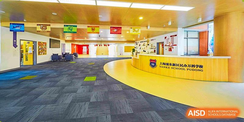 An open-plan, colorful learning or activity area at Vanke School Pudong with curved walls and a mix of yellow and blue flooring.