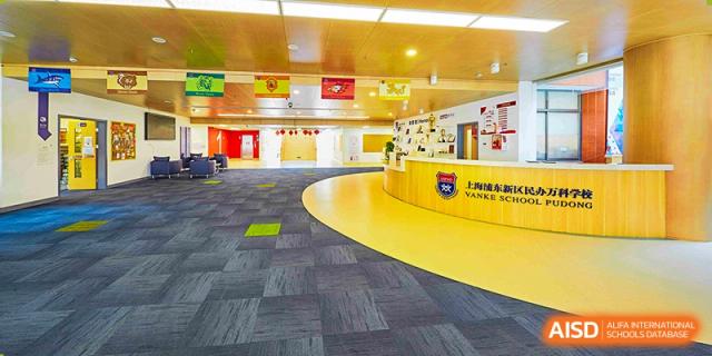 An open-plan, colorful learning or activity area at Vanke School Pudong with curved walls and a mix of yellow and blue flooring.