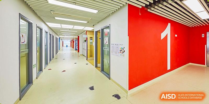 A clean, well-lit interior hallway at Vanke School Pudong with white walls, red accents, and a wide doorway.