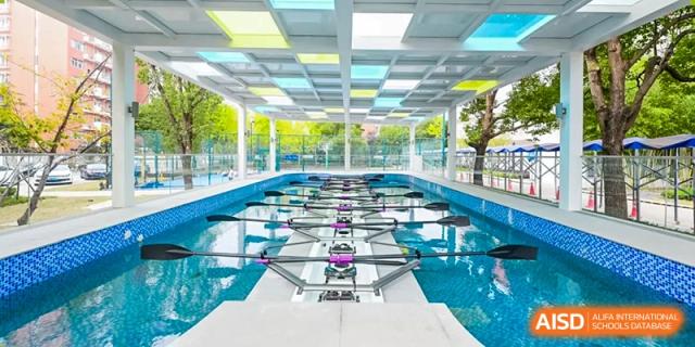 The indoor swimming pool facility at Vanke School Pudong, showing the lanes and ceiling light fixtures reflected on the water's surface.