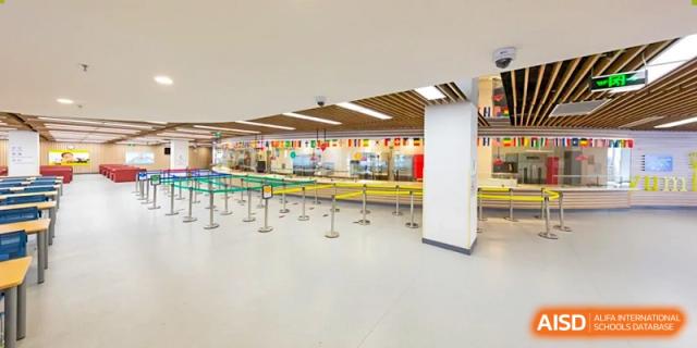 The school lunch serving line at Vanke School Pudong, showing barriers and queuing areas for students to collect their meals.