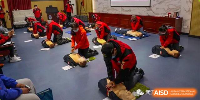 Students and staff from Wuhan Foreign Languages School International Division practicing CPR on mannequins during a first-aid training session.