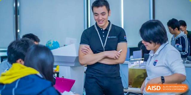 A teacher from Suzhou North America High School is smiling while holding a pen.