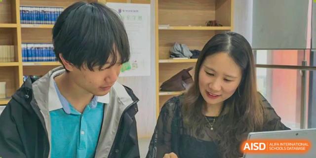 A male and female student from Suzhou North America High School are smiling while working on a project together.