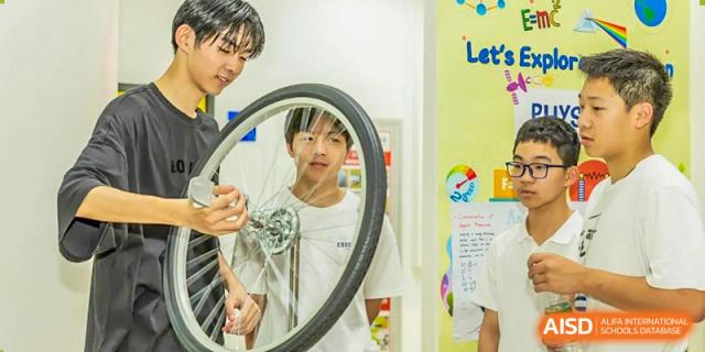 A student from Suzhou North America High School is looking at a model of a bicycle wheel in a classroom.