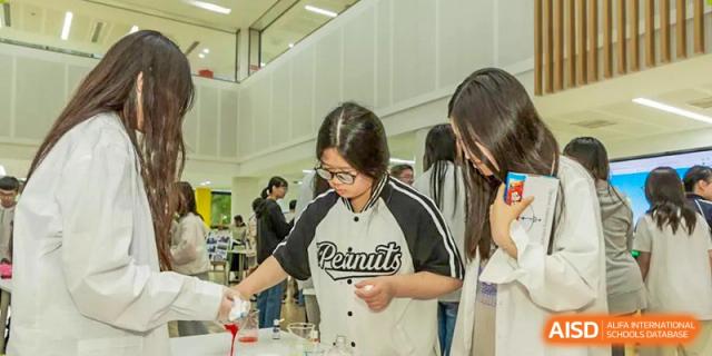 A female student from Suzhou North America High School is pouring a liquid from a beaker during a chemistry experiment.