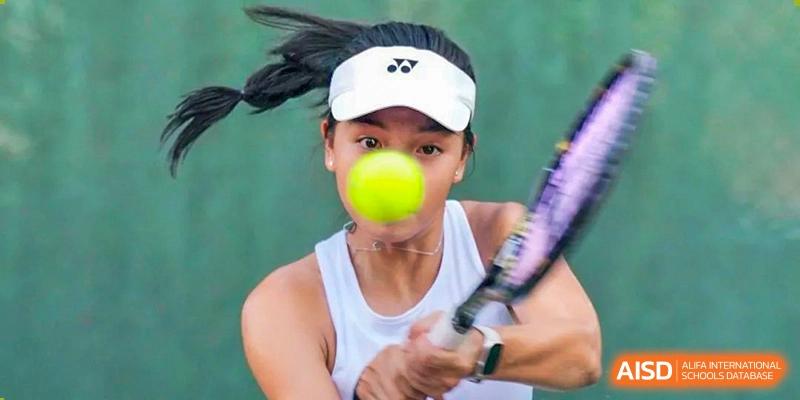 A female student from Suzhou North America High School is playing tennis and hitting a ball.