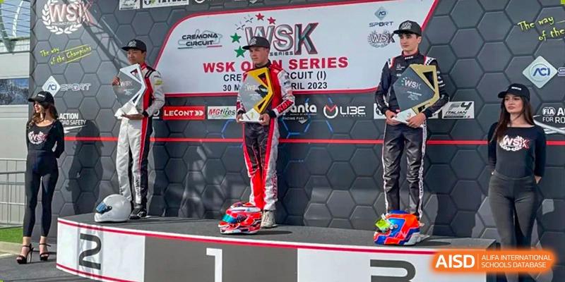 A student from Suzhou North America High School is standing on a podium with a trophy and a race suit.