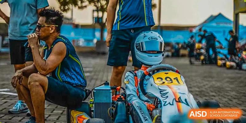 A student from Suzhou North America High School, wearing a helmet, sits in a go-kart.