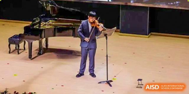 A student from Suzhou North America High School is playing the violin on a stage.