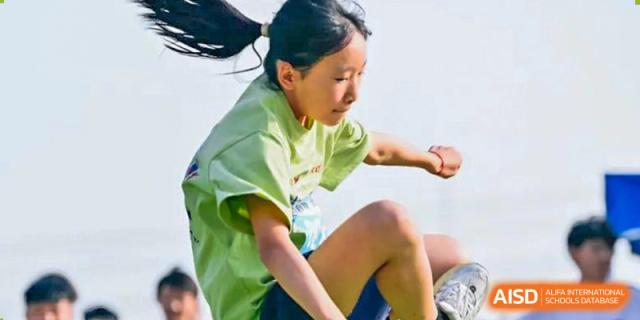 A student from Suzhou North America High School is participating in a long jump or high jump event.
