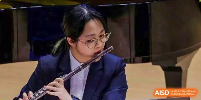 A student from Suzhou North America High School is playing the flute.