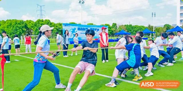 Students from Suzhou North America High School are playing tug-of-war on a sports field.