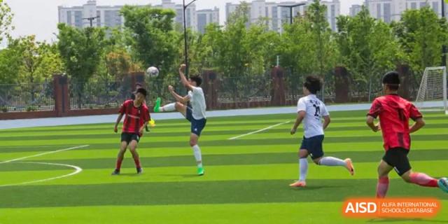A soccer player from Suzhou North America High School is kicking the ball on a green field.