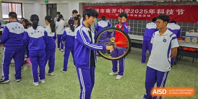 Students from Tianjin Nankai High School  are participating in a science or engineering project that involves a bicycle wheel.