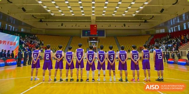 The Tianjin Nankai High School  boys' basketball team standing with their backs to the camera, showcasing their purple jerseys with numbers on a basketball court.