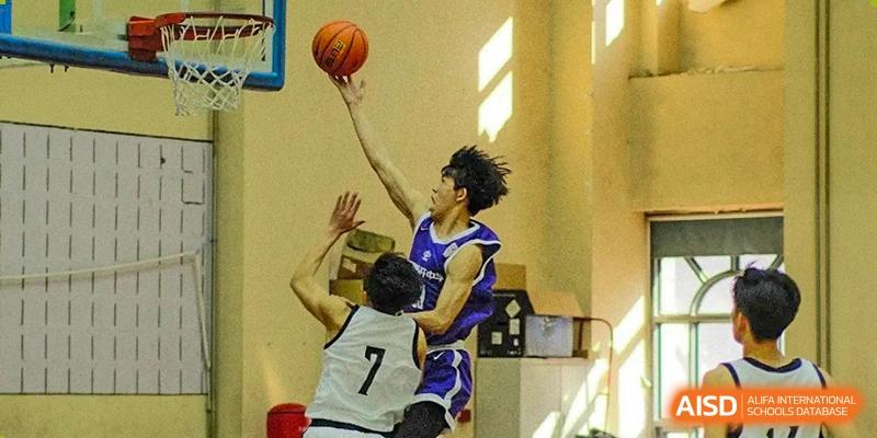 An action shot of a player from the Tianjin Nankai High School  team in a purple jersey, shooting a basketball over a defender.