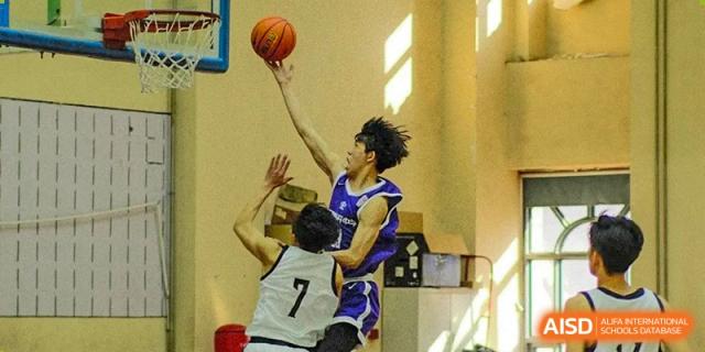 An action shot of a player from the Tianjin Nankai High School  team in a purple jersey, shooting a basketball over a defender.