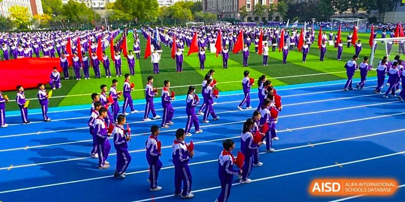 An aerial view of students from Tianjin Nankai High School participating in a large outdoor group activity, possibly a synchronized performance or a school assembly.