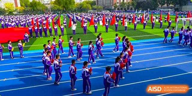 An aerial view of students from Tianjin Nankai High School participating in a large outdoor group activity, possibly a synchronized performance or a school assembly.