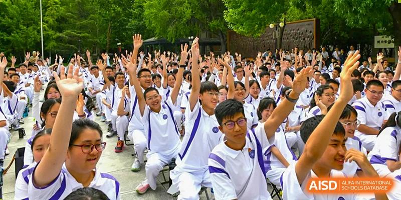 Students from Tianjin Nankai High School  are excitedly raising their hands and cheering at a school event.