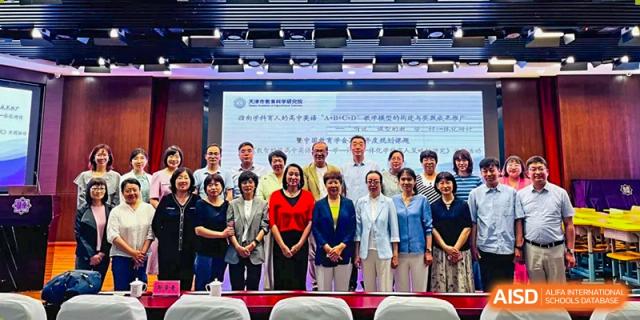 A group of students and teachers from Tianjin Nankai High School are posing for a group photo in front of a screen with school information.