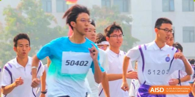 Students from Tianjin Nankai High School participating in a running event, with a student in the foreground wearing a numbered bib.