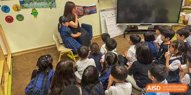 A teacher from Wellington College International Tianjin reads to a group of young students in a classroom.