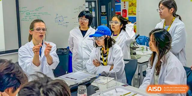 A group of female students from Wellington College International Tianjin in lab coats works on a project together.