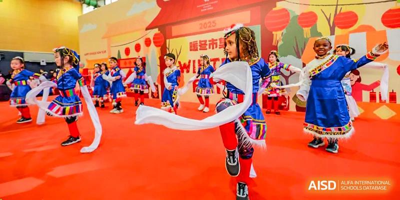 A young student from Wellington College International Tianjin performs a traditional ribbon dance on a red stage.