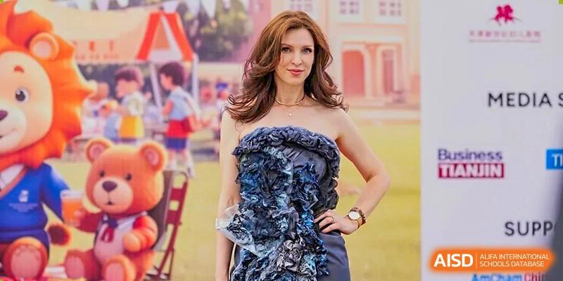 A female teacher or staff member from Wellington College International Tianjin poses for a portrait outdoors.