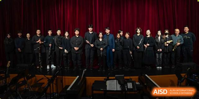 A group of male and female students from Wellington College International Tianjin stands together on a stage after a performance.