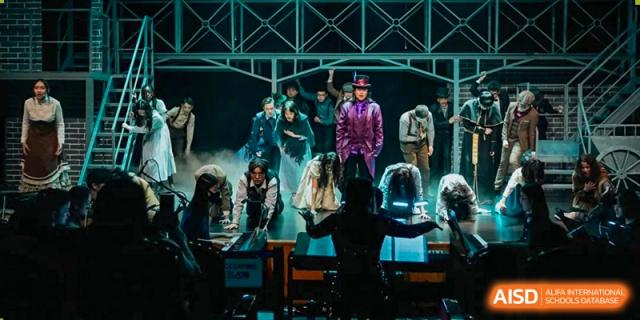 Students from Wellington College International Tianjin perform a choreographed dance on a stage with vibrant lighting.