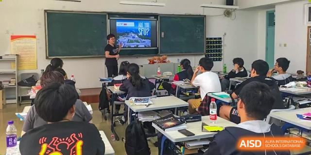 A class session in progress with students seated at desks and an instructor presenting on a large screen at Yang Guang Qing International School of Beijing.