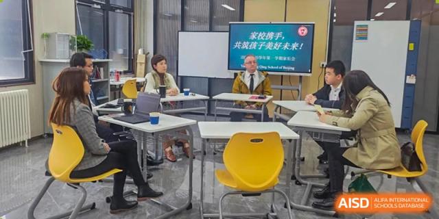 A small group meeting or consultation with an instructor at a table, featuring bright yellow chairs at Yang Guang Qing International School of Beijing.