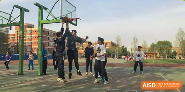 Students playing basketball on an outdoor court at Yang Guang Qing International School of Beijing.