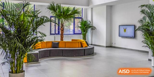 Modern and bright interior lobby area with curved seating and large potted plants at Yang Guang Qing International School of Beijing.