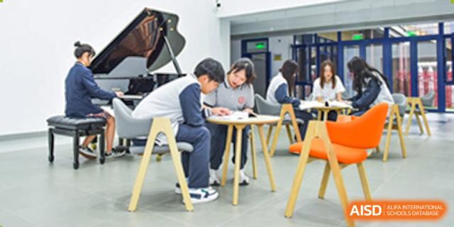 Two students sitting at a small table and studying or collaborating indoors at Yang Guang Qing International School of Beijing.