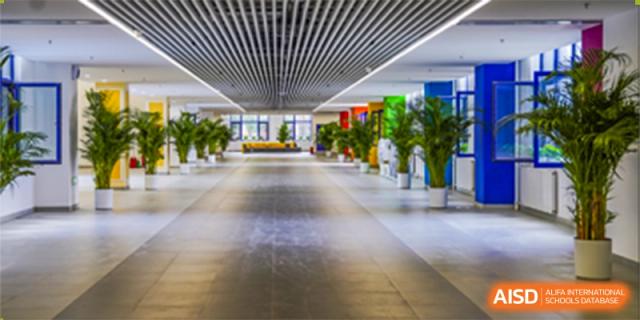 A long, bright, and spacious interior school hallway with natural light and potted plants at Yang Guang Qing International School of Beijing.
