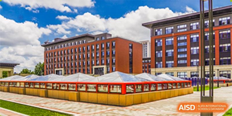 A view of a modern, red-brick dormitory or academic building with a covered outdoor area at Yang Guang Qing International School of Beijing.