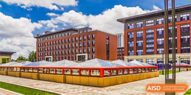 A view of a modern, red-brick dormitory or academic building with a covered outdoor area at Yang Guang Qing International School of Beijing.