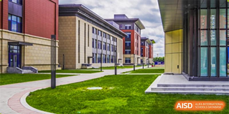 An exterior view of a school building with well-maintained green lawn and landscaping at Yang Guang Qing International School of Beijing.