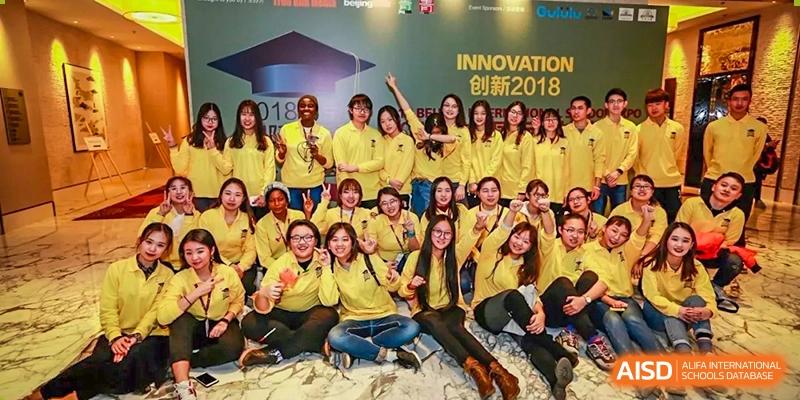 A large group of people wearing yellow shirts posing for a cheerful group photo at an event at Yang Guang Qing International School of Beijing.
