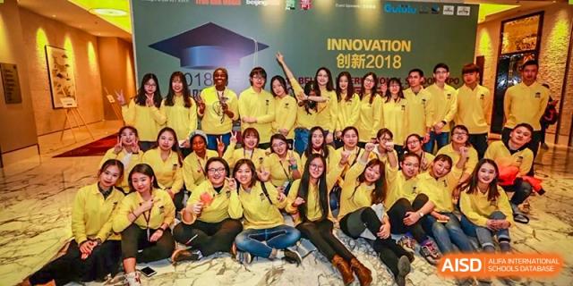 A large group of people wearing yellow shirts posing for a cheerful group photo at an event at Yang Guang Qing International School of Beijing.