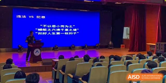 Students seated in an auditorium watching a presentation or video on a large blue screen at Yang Guang Qing International School of Beijing.