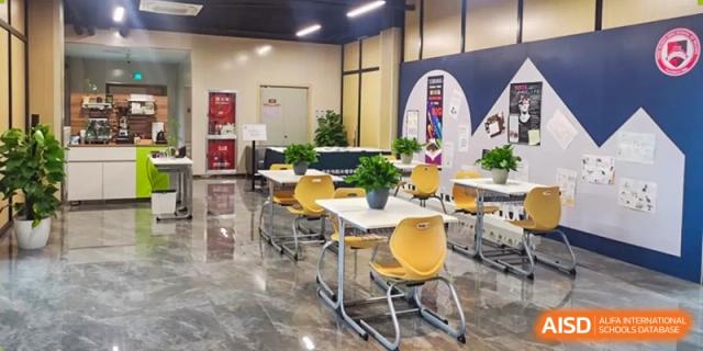 A bright and modern student common area or small dining space with yellow chairs at Yang Guang Qing International School of Beijing.