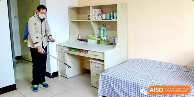 A view of a typical student dormitory room with a desk, shelving unit, and bed at Yang Guang Qing International School of Beijing.