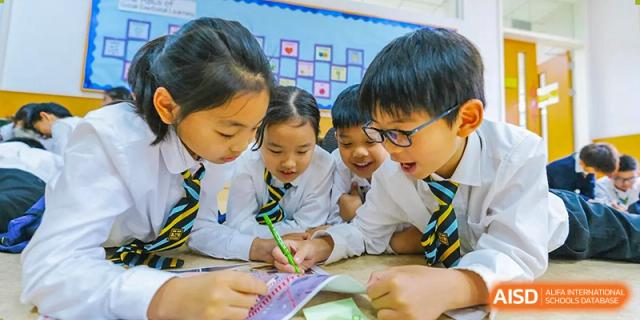 Young Huili School Shanghai students in uniform collaborating intently on a project or activity at a table.
