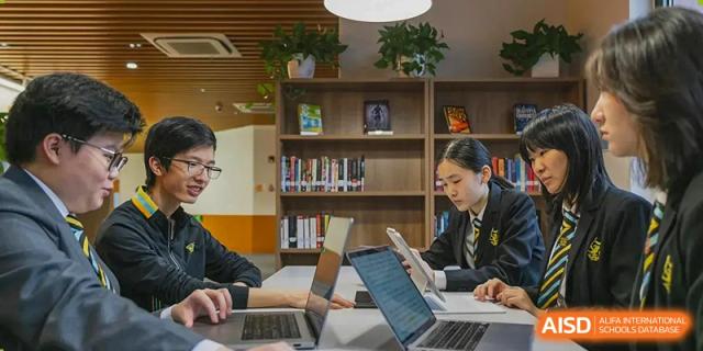 Huili School Shanghai students working on laptops in a well-lit, modern library setting.