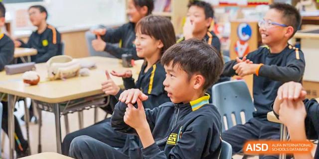 Huili School Shanghai students in black and yellow sports uniforms engaged in an animated group discussion.